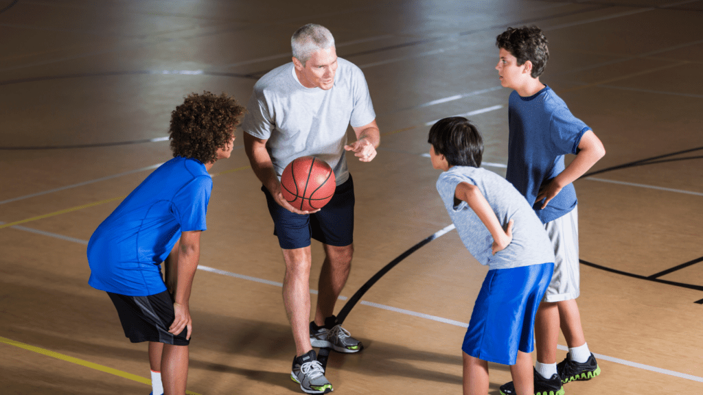 Entrenador habla a tres jugadores de baloncesto. Los retos del entrenador de Minibasket
