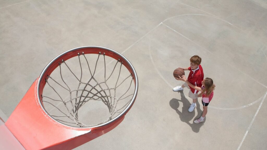 Dos jugadores con un balón y una canasta en vista desde el tablero. Los retos del entrenador de Minibasket